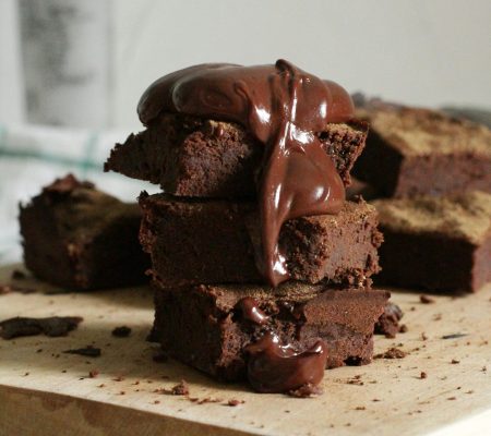Delicious stack of chocolate brownies drizzled with gooey syrup on a wooden board.